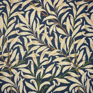 May include: Close-up of a fabric featuring a repeating pattern of beige leaves and brown stems set against a dark blue backdrop. The leaves have a textured look, and the design evokes a botanical illustration.