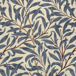 May include: A woven fabric featuring a repeating botanical pattern of dark blue willow leaves and thin brown branches set against a cream-coloured background. The textile displays a textured weave with a dense arrangement of foliage across the surface.