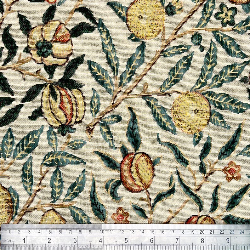 May include: A white fabric with a repeating pattern of green leaves, yellow and orange fruit, and small white flowers. The fabric is measured with a ruler in inches.