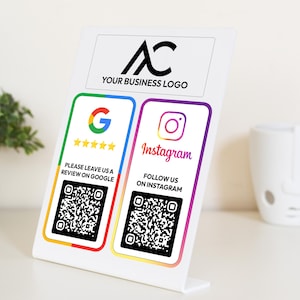 May include: White sign with a black logo "AC" and the text "YOUR BUSINESS LOGO". The sign has two sections with QR codes and text. The left section has a Google logo, five stars, and the text "PLEASE LEAVE US A REVIEW ON GOOGLE". The right section has an Instagram logo, the text "Instagram", and the text "FOLLOW US ON INSTAGRAM".
