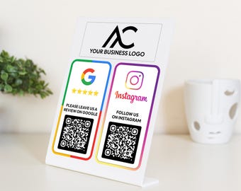 Op de afbeelding: Een wit bord met een zwart logo "AC" en de tekst "YOUR BUSINESS LOGO". Het bord heeft twee secties met QR-codes en tekst. De linker sectie heeft een Google-logo, vijf sterren en de tekst "PLEASE LEAVE US A REVIEW ON GOOGLE". De rechter sectie heeft een Instagram-logo, de tekst "Instagram" en de tekst "FOLLOW US ON INSTAGRAM".