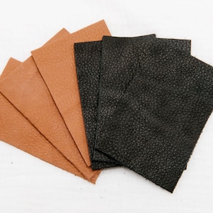 May include: A close-up of six leather squares, four are brown and two are black. The leather squares are arranged in a fan shape.