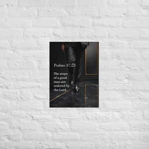 Op de afbeelding: Een ingelijste print met een persoon in een zwart pak en nette schoenen die loopt op een zwart-gouden tegelvloer. De tekst "Psalms 37:23" en een citaat zijn in het wit weergegeven.
