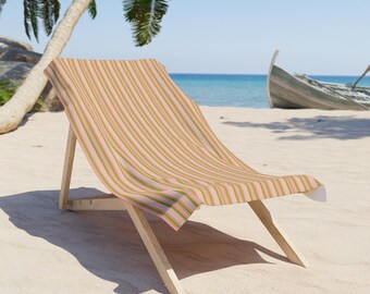 Może przedstawiać: Różowo-zielone, pasiasty leżak plażowy z drewnianym stelażem. Leżak stoi na piaszczystej plaży z palmą i łodzią w tle.