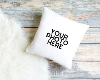 May include: White cushion with the text "YOUR PHOTO HERE" printed on it. The cushion is lying on a white faux fur rug and a light wood surface.