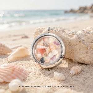 May include: A silver-colored, round floating locket necklace filled with various seashells. The necklace is on a sandy beach with seashells scattered around. The text at the bottom reads "REAL MINI SEASHELL FLOATING LOCKET NECKLACE".