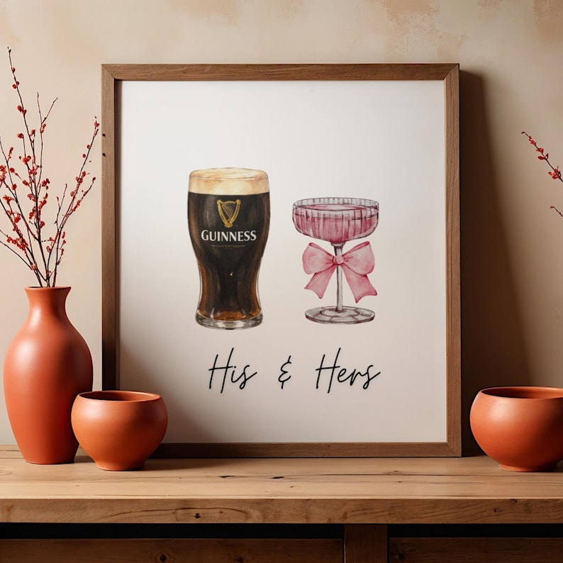Puede incluir: Impresi&oacute;n en acuarela enmarcada que muestra una pinta de Guinness y una copa de champ&aacute;n rosa con un lazo. Las palabras "His & Hers" est&aacute;n escritas debajo. El marco es de madera.