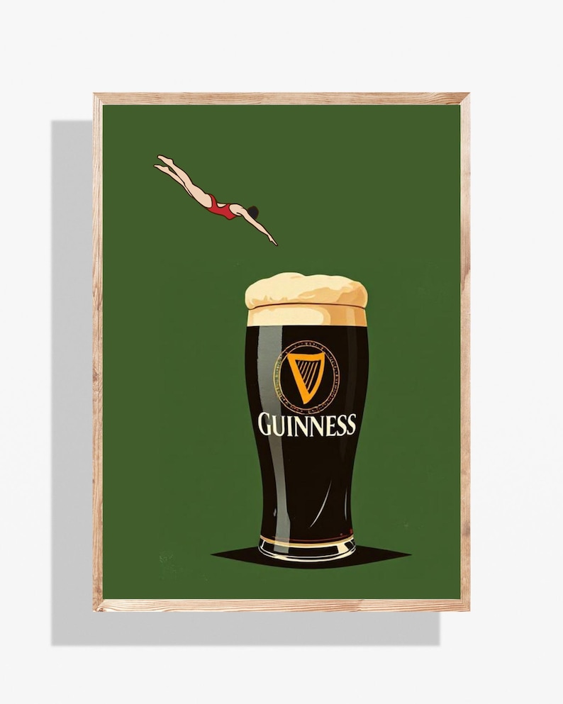 May include: A framed print featuring a pint of Guinness stout with a diver in a red swimsuit. The Guinness glass is black with a white head and the Guinness logo. The background is a solid dark green.