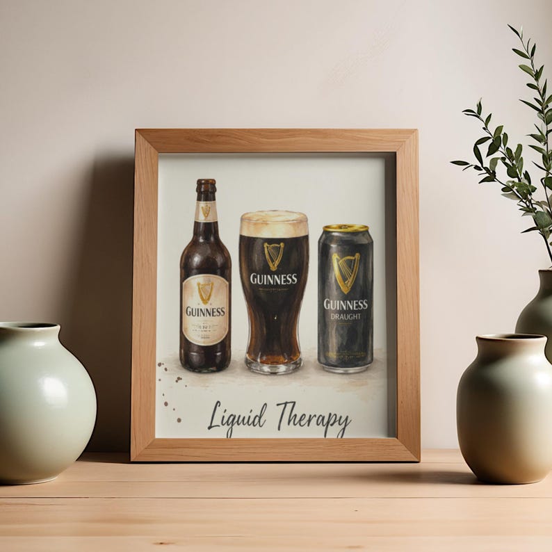 May include: A framed print depicting a bottle, a pint glass, and a can of Guinness. The image is in a watercolour style, with the Guinness logo visible. The words "Liquid Therapy" are written at the bottom of the print.