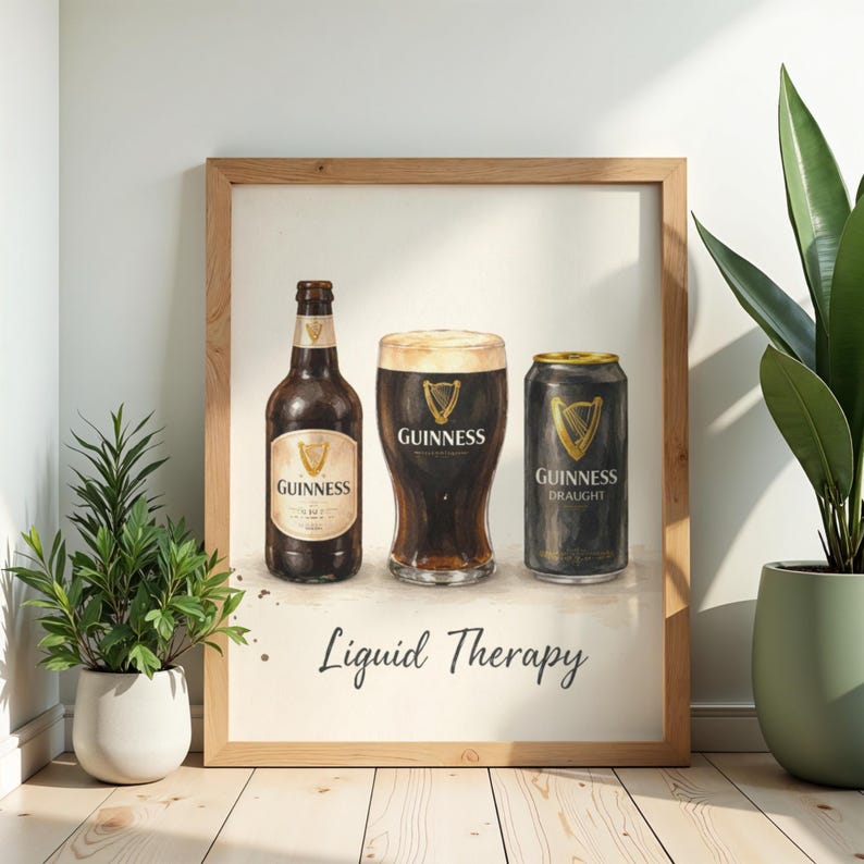 May include: A framed print depicting a bottle, a pint glass, and a can of Guinness stout. The print is in a light wooden frame and has the words "Liquid Therapy" at the bottom. The Guinness logo is visible on each item.