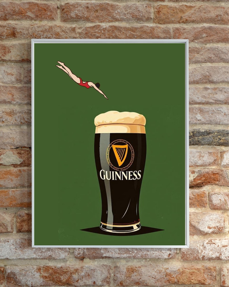 May include: A framed print featuring a pint of Guinness stout with a diver in a red swimsuit above it. The Guinness glass is black with a white head and the Guinness logo. The background is a solid green.