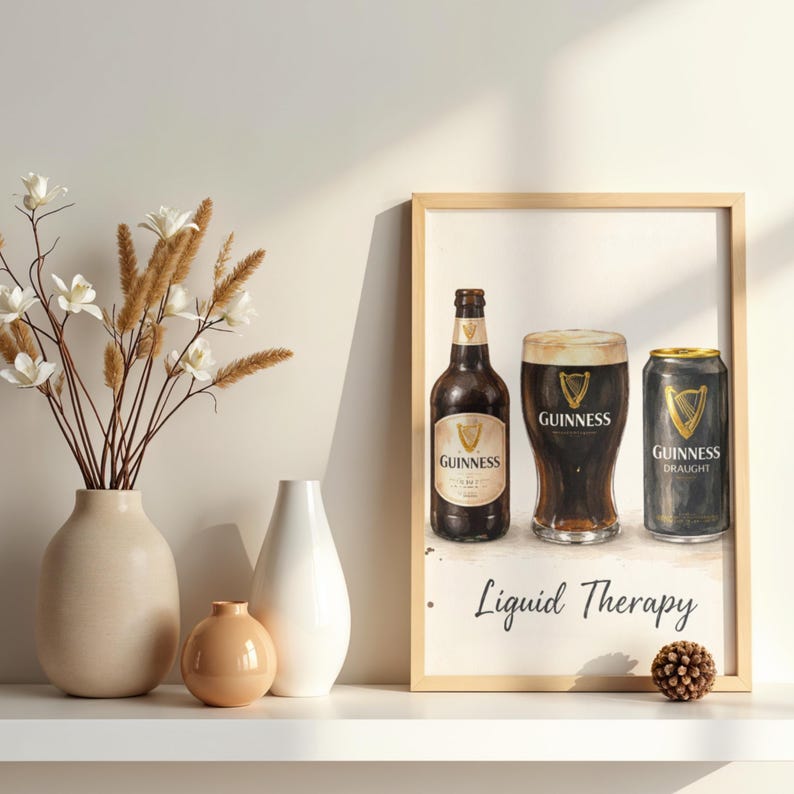 May include: A framed print depicting a Guinness bottle, pint, and can. The print includes the words "Liquid Therapy". The print is displayed on a white shelf with vases and decorative items.