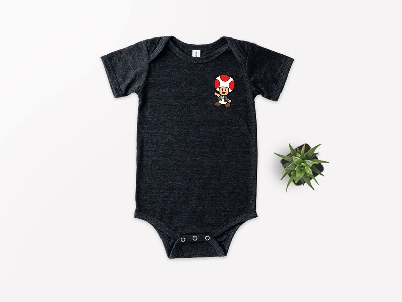 May include: A dark grey baby onesie with a cartoon image of a mushroom character with a red cap and brown body.