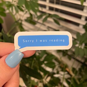 May include: A white sticker with a blue speech bubble that says "Sorry I was reading".