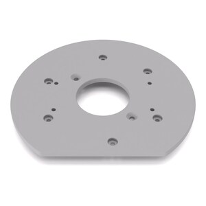Peut inclure: Une plaque de montage circulaire gris clair avec un bord inférieur plat. La plaque présente une grande ouverture circulaire centrale entourée de plusieurs petits trous de vis fraisés régulièrement espacés pour une fixation sécurisée.