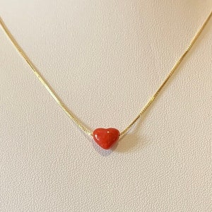 Peut inclure: Un collier en chaîne dorée avec un petit pendentif en forme de cœur rouge.