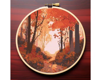May include: A cross-stitch landscape of a forest scene in autumn colors. The design is framed in a wooden embroidery hoop. The scene features trees, a path, and a bright light in the distance, with shades of orange, brown, and yellow.