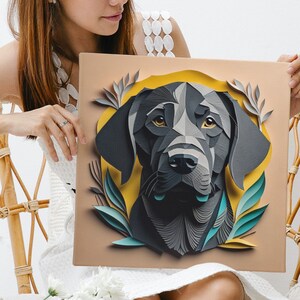 Pu&ograve; includere: Una donna con un vestito bianco tiene in mano un'opera d'arte in carta raffigurante un cane nero con foglie verdi. Il cane &egrave; in un cerchio giallo su uno sfondo marrone. La donna &egrave; seduta su una sedia di vimini con una coperta bianca sulle sue ginocchia.