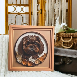 Pu&ograve; includere: Un'opera d'arte in carta incorniciata di un cane Shih Tzu marrone con un bordo floreale. Il cane guarda direttamente lo spettatore. La cornice &egrave; in legno marrone chiaro.