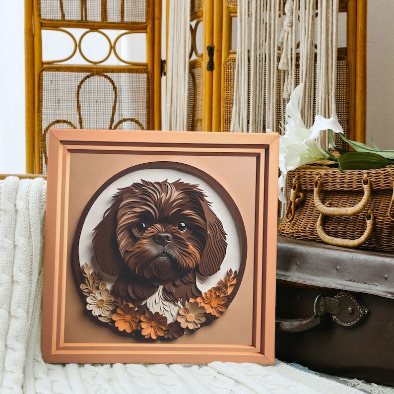 Pu&ograve; includere: Un'opera d'arte in carta incorniciata di un cane Shih Tzu marrone con un bordo floreale. Il cane guarda direttamente lo spettatore. La cornice &egrave; in legno marrone chiaro.