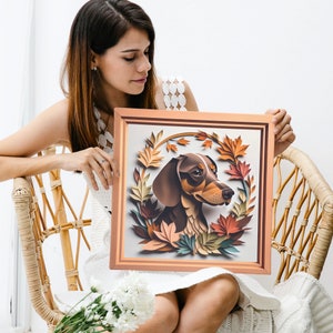 May include: A framed illustration of a brown and black dachshund dog with brown eyes, surrounded by fall-colored leaves in shades of orange, yellow, and red. The frame is a light brown wood with a gold trim.