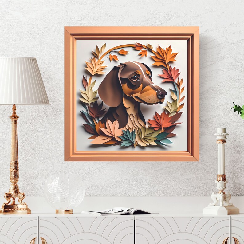 May include: A framed illustration of a brown and black dachshund dog with brown eyes, surrounded by a wreath of colorful paper leaves in shades of orange, yellow, green, and brown.