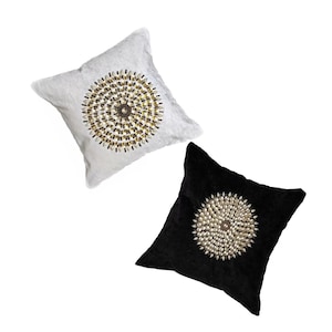 May include: Two decorative throw pillows with a circular design of gold and white beads. One pillow is white and the other is black.