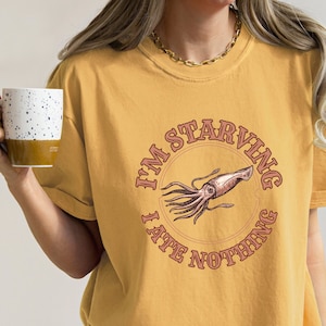 May include: A yellow t-shirt with a graphic of a squid and the text "I'm starving I ate nothing".