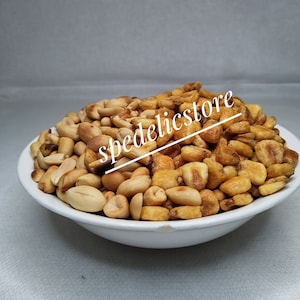 May include: A white bowl filled with a mixture of roasted peanuts and corn kernels.