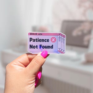 May include: A pink and white sticker with the text "ERROR 404 Patience Not Found" and a red X. The sticker is held in a hand with pink nail polish.
