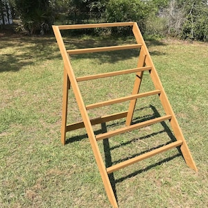 May include: A wooden A-frame display stand with six shelves. The stand is made of natural wood and has a rustic look.