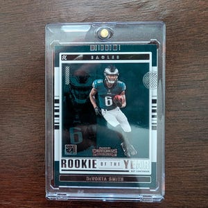 May include: A green and white football card featuring a player in a green and white uniform with the number 6. The card is titled "Rookie of the Year" and features the player's name "Devonta Smith".
