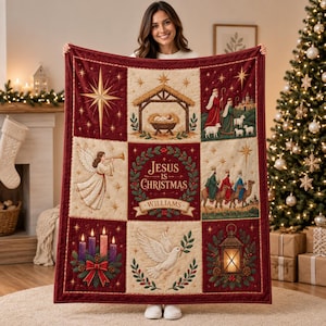 May include: A rectangular quilted throw blanket featuring a grid of nine panels with Christmas-themed illustrations, including a nativity scene, an angel, the Three Wise Men, a dove, and candles, with the text Jesus Is Christmas and Williams.
