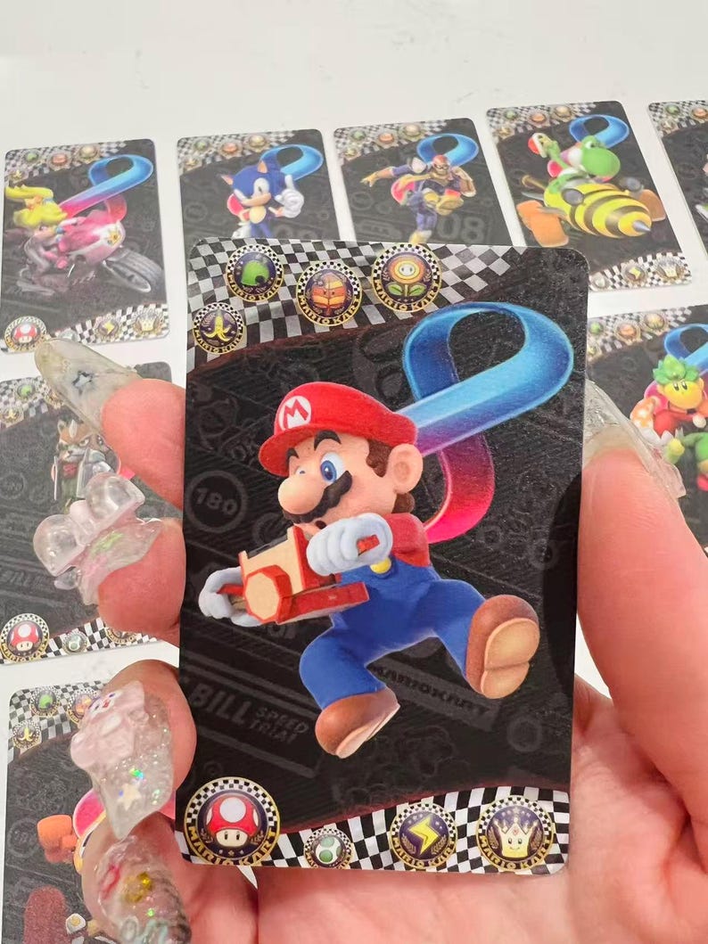 May include: A trading card featuring Mario from the Mario Kart series. Mario is shown in his red hat and blue overalls, holding a kart. The card has a black background with a checkered pattern and various icons.