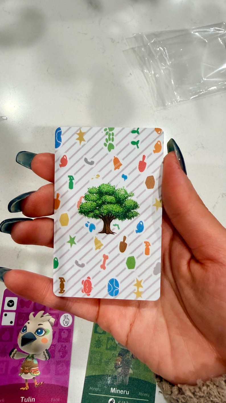 May include: A rectangular trading card featuring a central green tree illustration surrounded by a pattern of small, colourful icons including stars, bells, spray bottles, and paw prints against a white background with diagonal grey stripes.