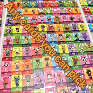 May include: A large collection of rectangular Animal Crossing trading cards arranged in a grid, each featuring a unique character illustration, a coloured background, and game-related icons. The text Any cards you can pick is overlaid.