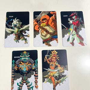 May include: Five rectangular trading cards featuring illustrated characters. The cards are labeled Tulin, Yunobo, Sidon, Mineru, and Riju. Each card displays a unique character in a dynamic pose against a black and white patterned background.