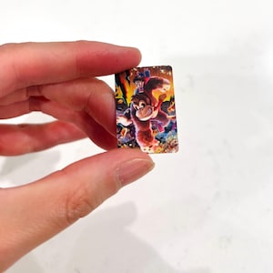 May include: A small, rectangular image with a colourful illustration of a cartoon ape character with a smaller figure riding on its back. The image has a vibrant, detailed design with a mix of warm and cool colours.