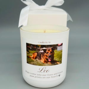 May include: White candle with a photo of a German Shepherd dog on the front. The candle has the text "Candles by MJ" and "Leo" on the front. The text below the photo reads "Dogs come into our lives and leave paw prints on our hearts".