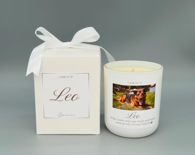May include: White candle with a photo of a German Shepherd dog on the front. The candle has the words "Candles by Mi" and "Leo" printed on it. The text below the photo reads "Dogs come into our lives and leave paw prints on our hearts".
