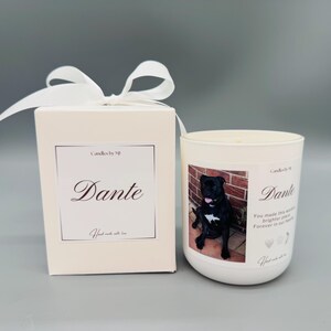 May include: White candle with a black and white photo of a dog on the front. The candle is in a white jar with a white label that says "Candles by MJ" and "Dante". The label also includes the text "You made this world brighter, our hearts forever in your paws".