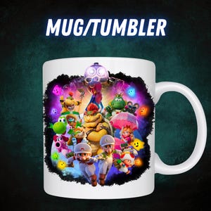 Op de afbeelding: Witte keramische mok met een kleurrijke afbeelding van videogamepersonages. De mok heeft een groot oor en de tekst "MUG/TUMBLER" in het wit. Het ontwerp bevat personages als Mario, Luigi en Bowser.
