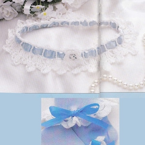 May include: A delicate, handmade set featuring a white crocheted garter with light blue ribbon accents and a matching pair of light blue socks. The socks are adorned with white lace and light blue bows, creating a romantic, vintage aesthetic.