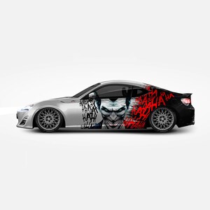 May include: A white car with a black and red graphic of the Joker from Batman. The graphic includes the Joker's face and the word "HA" repeated many times.