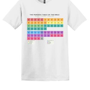 May include: A white short-sleeved t-shirt featuring a graphic print titled THE PERIODIC TABLE OF THE BIBLE. The design displays a grid of colourful squares with two-letter abbreviations representing books of the Bible, organised by category.
