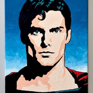 May include: A canvas painting featuring a stylized portrait of a figure with dark hair and blue eyes. The artwork uses bold black shadows against a light peach skin tone, set against a vibrant blue background with a red accent at the bottom.