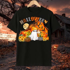 Könnte beinhalten: Ein schwarzes Kurzarm-T-Shirt mit einem Grafikdruck und dem Text HALLOWEEN VIBES. Das Motiv zeigt einen weißen Geist mit einer orangefarbenen Mütze, der einen Kaffeebecher hält, umgeben von Kürbissen, Sonnenblumen und fliegenden Fledermäusen.
