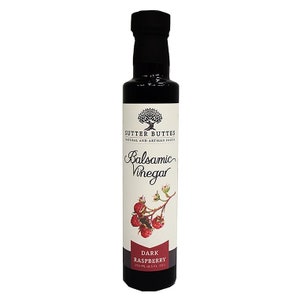 May include: A glass bottle of Sutter Buttes Dark Raspberry Balsamic Vinegar. The bottle is labeled with a drawing of raspberries and a tree. The label also says "Natural and Artisan Foods".