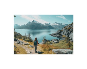 May include: A woman wearing a backpack walks on a path towards a body of water surrounded by mountains. The water is a deep blue and the mountains are covered in snow.