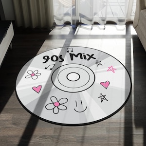 May include: A round white rug with a black and white design of a cassette tape. The tape has the text "90s Mix" on it and is surrounded by hearts, stars, flowers, and a smiley face.